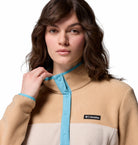 Woman wearing a beige and white Columbia jacket with a blue trim on a white background