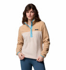 Woman wearing a beige and blue pullover with a visible brand logo on a white background