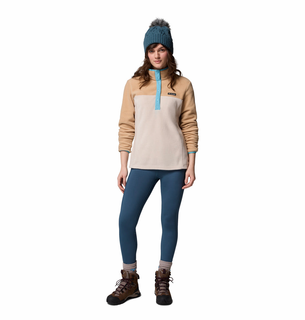 Person wearing a beige and blue pullover with blue leggings and brown boots on a white background