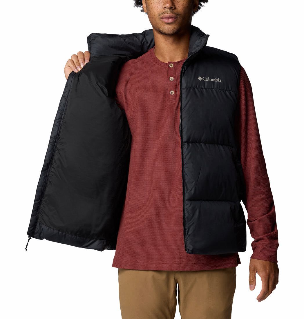 Person wearing a black Columbia vest over a red shirt on a white background