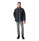 Man wearing a black jacket, blue shirt, gray pants, and black boots on a white background