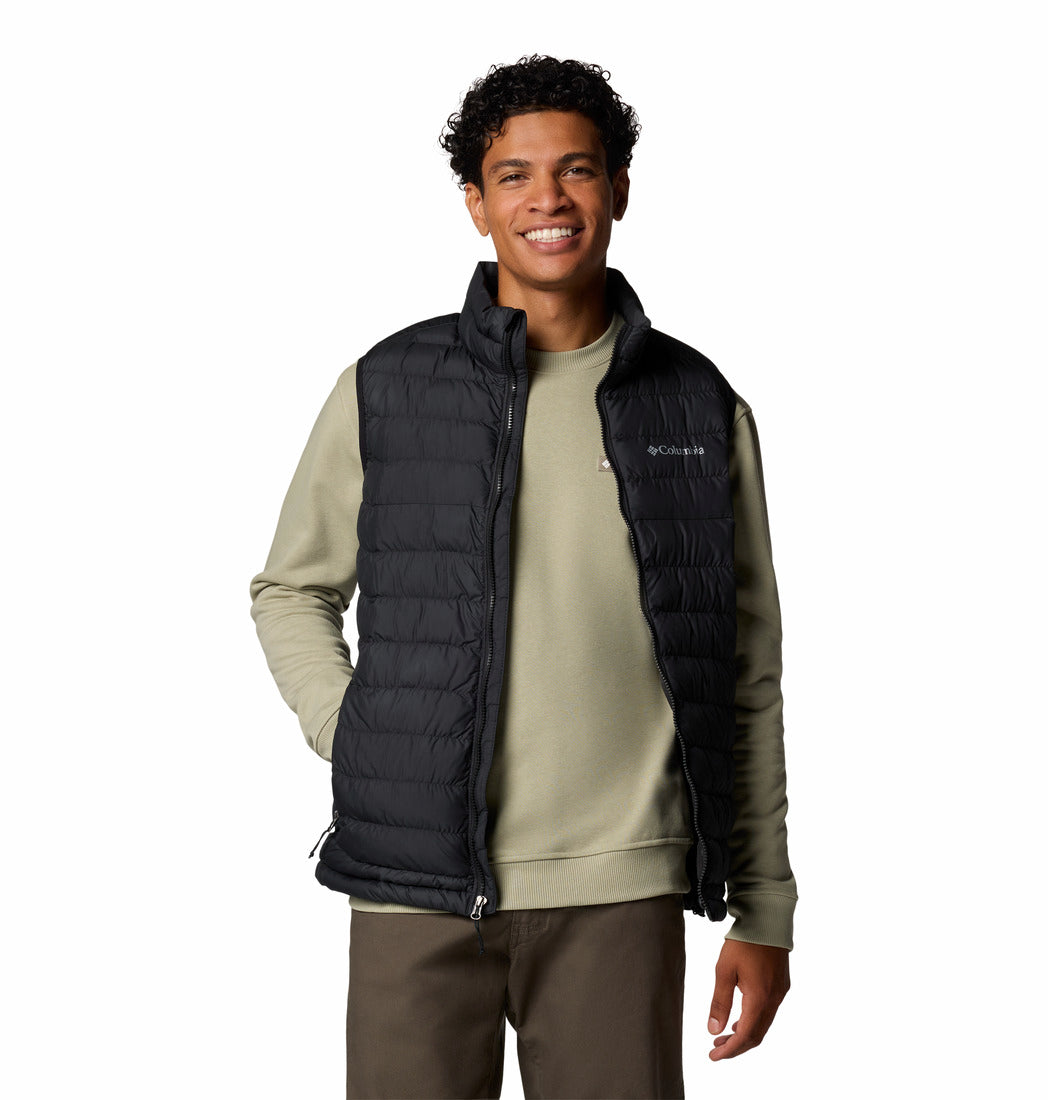 Man wearing a black puffer vest over a green shirt on a white background
