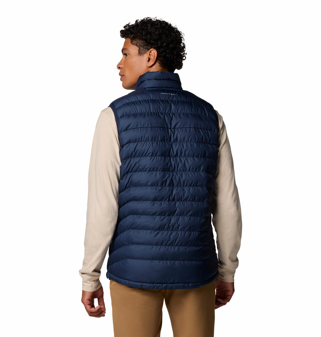 Person wearing a navy puffer vest over a beige shirt on a white background
