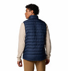 Person wearing a navy puffer vest over a beige shirt on a white background