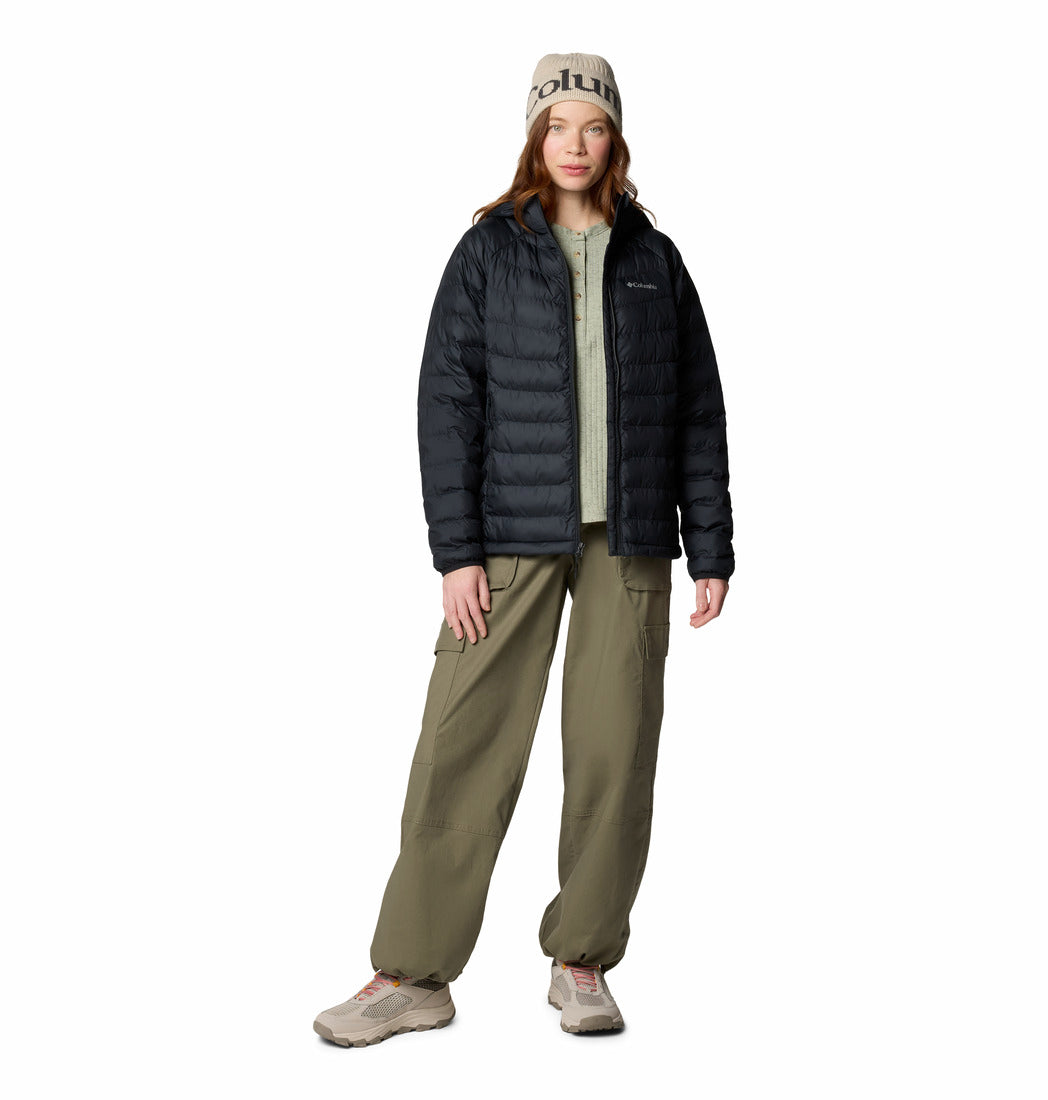 Person wearing a black puffer jacket, beige pants, and a beanie with a brand logo on a white background