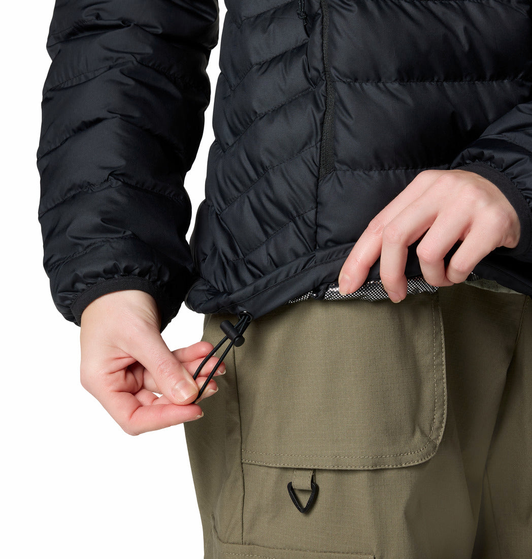 Person wearing a black puffer jacket and green pants with a white background