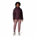 Woman wearing a dark purple jacket and pink pants on a white background