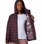 Woman wearing a purple puffer jacket with a white shirt underneath on a white background