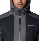 Person wearing a Columbia jacket with a hood on a plain background