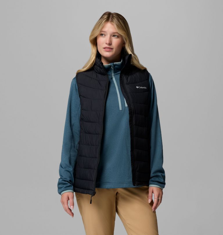 Woman wearing a blue jacket with a black puffer vest on a gray background