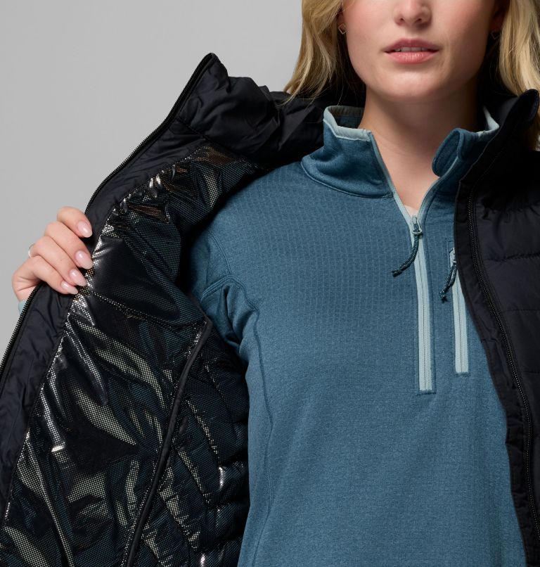 Person wearing a blue pullover with a black jacket over it against a gray background