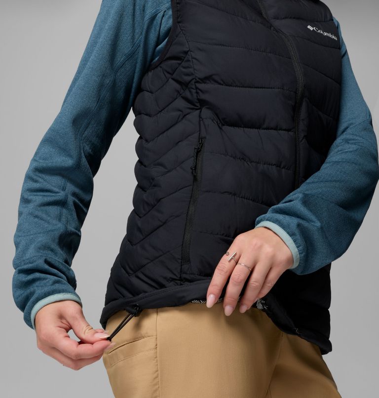 Person wearing a black puffer vest over a blue long-sleeve shirt on a gray background