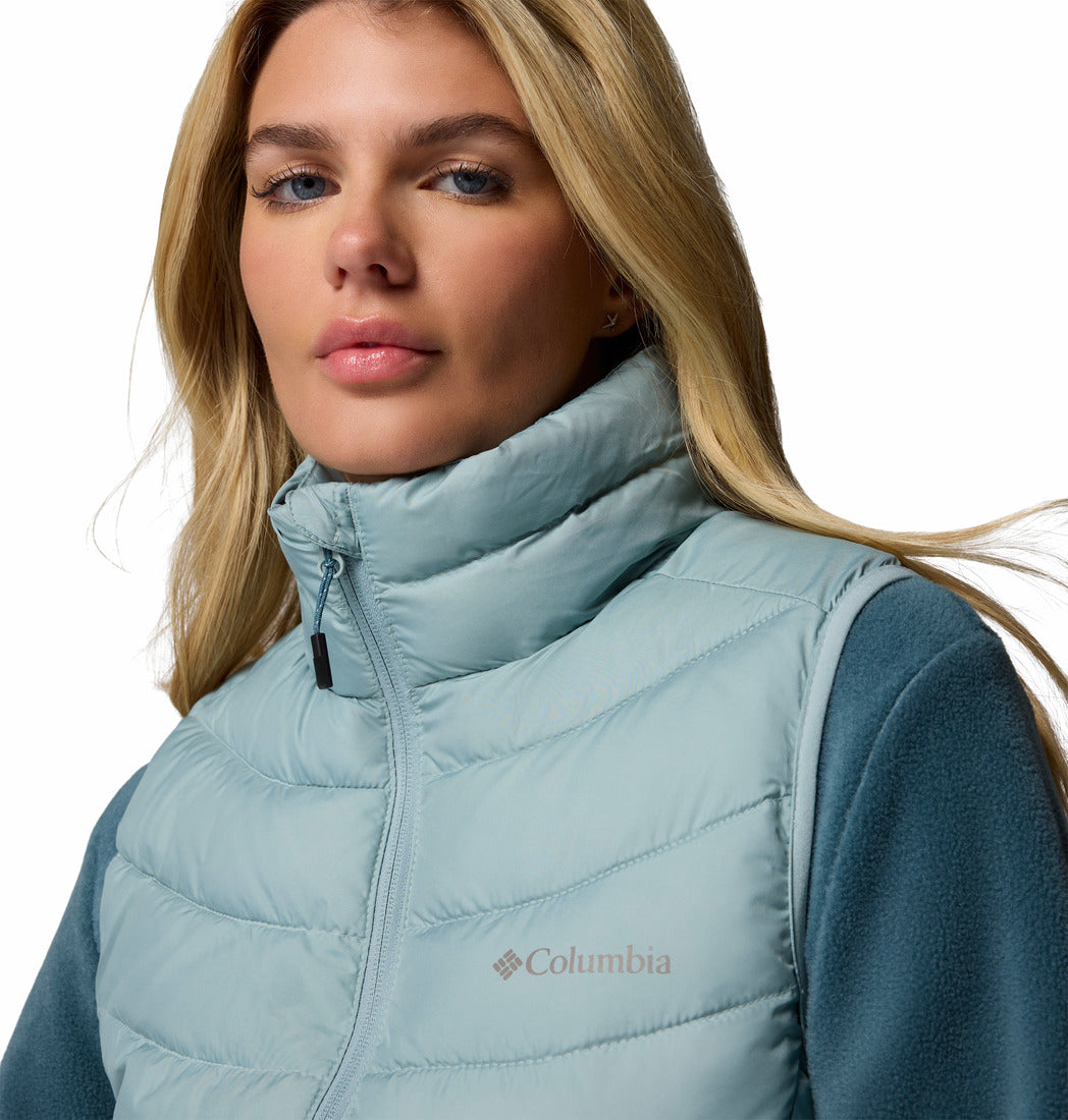 Woman wearing a light blue Columbia puffer vest on a white background