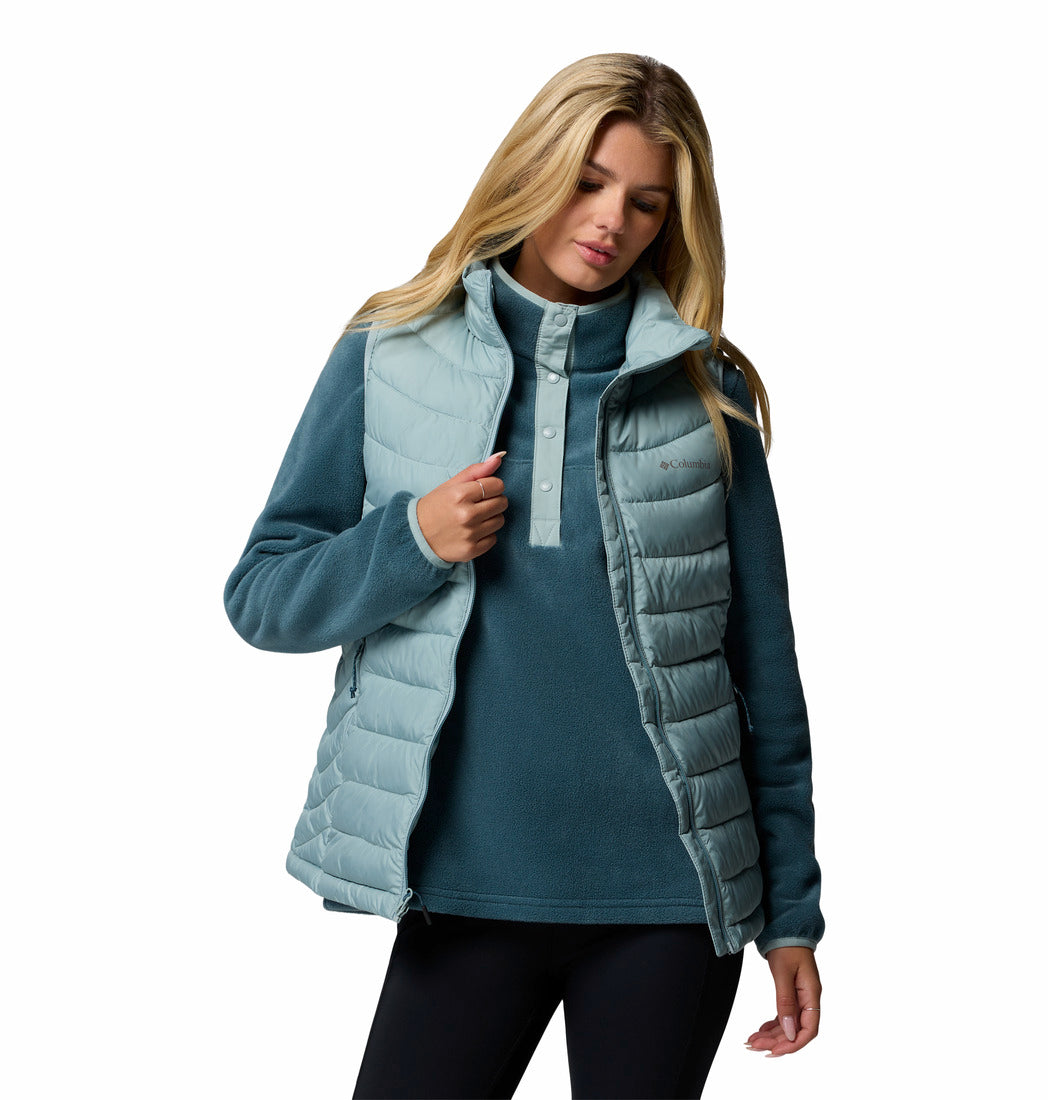 Woman wearing a light blue puffer vest over a teal shirt on a white background
