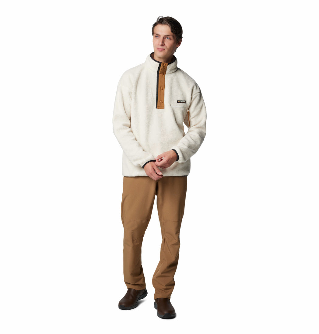 Man wearing a cream-colored pullover with a brown zipper and tan pants on a white background