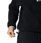 Person wearing a black fleece jacket with a white background