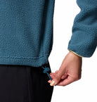 Person wearing a blue fleece jacket with a hand adjusting the drawstring.