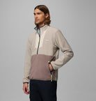 Man wearing a two-tone jacket with a gray and brown design on a gray background