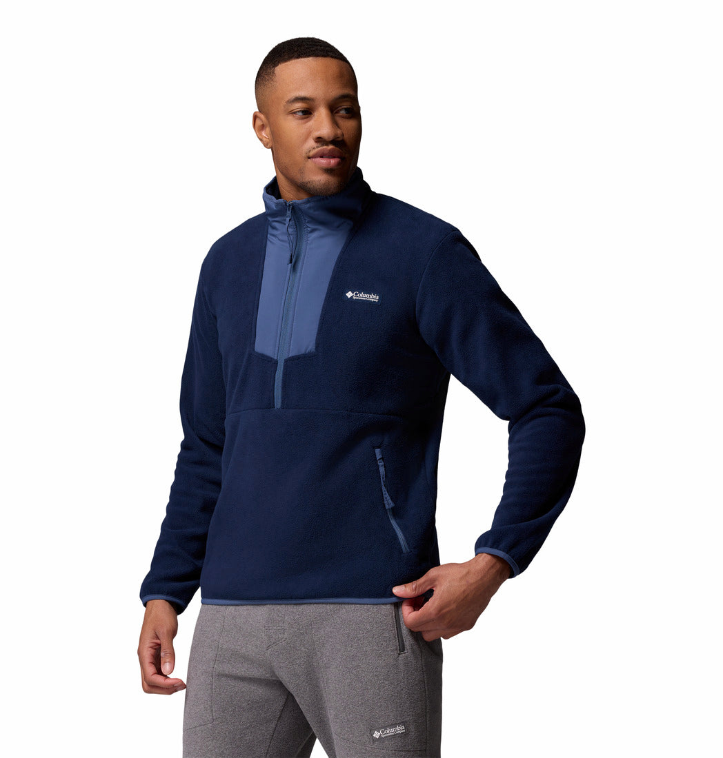 Man wearing a navy blue pullover with a brand logo on a white background