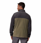Man wearing a two-tone jacket with dark gray and green sections on a white background