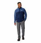 Man wearing a blue pullover and gray pants on a white background
