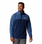 Man wearing a blue pullover with a brand logo on a white background