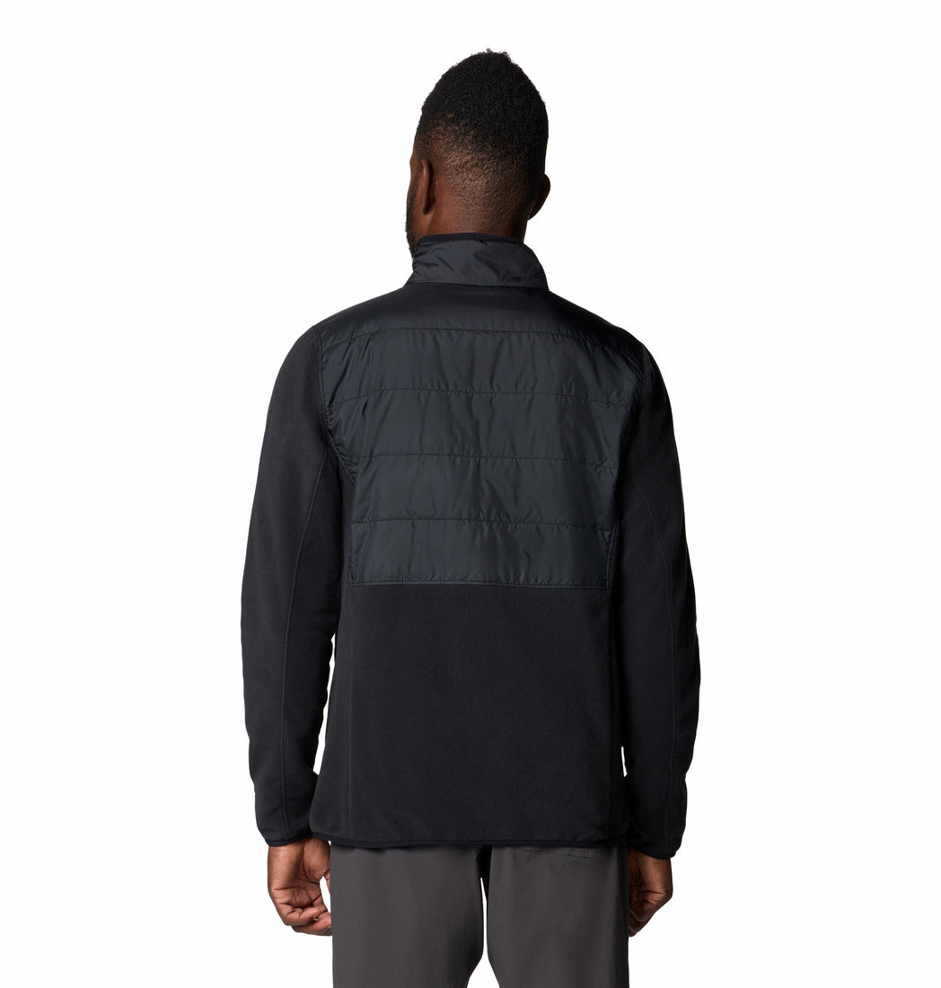 Person wearing a black jacket with quilted back panel on a white background