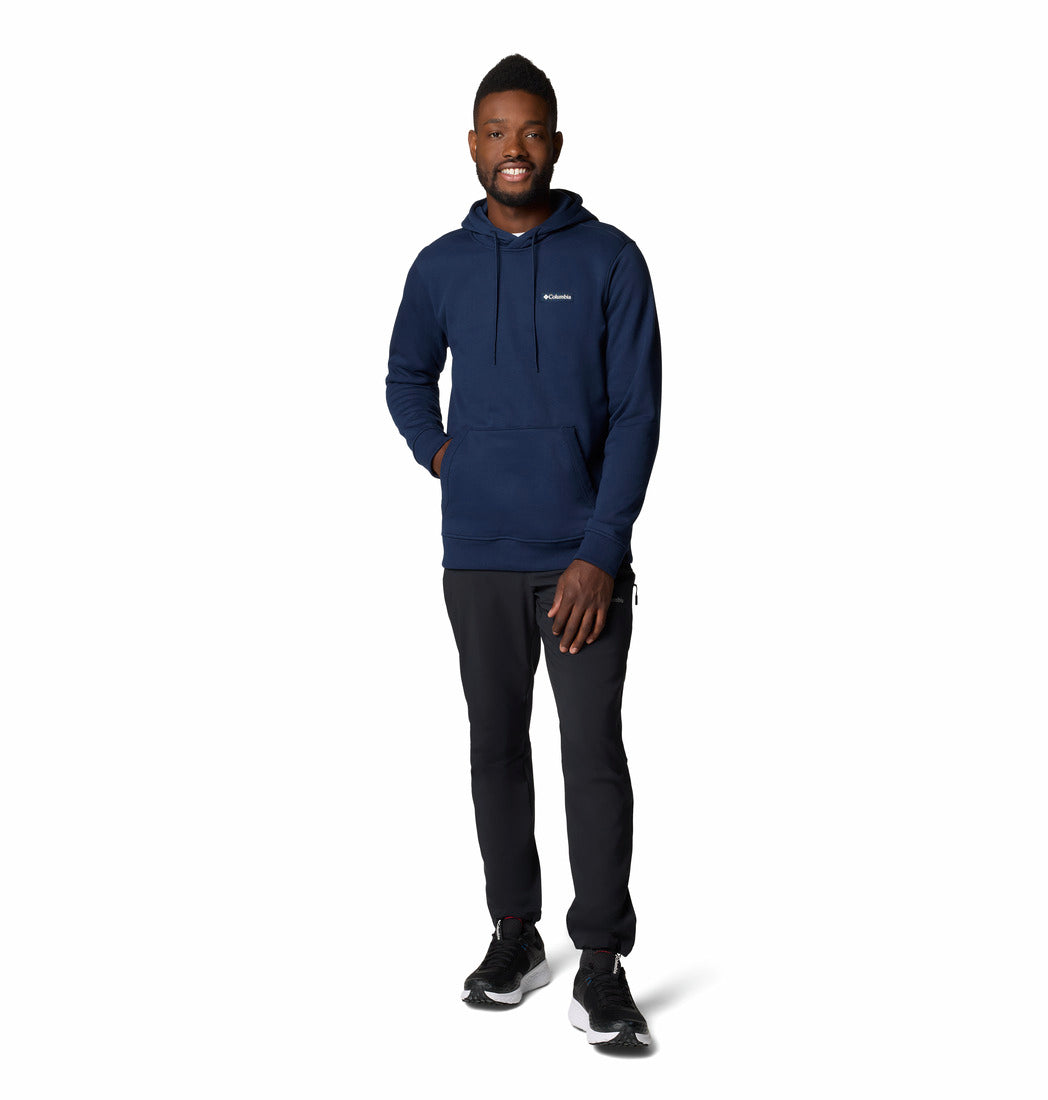 Man wearing a navy hoodie and black pants on a white background