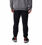 Person wearing a gray sweatshirt and black jogger pants on a white background