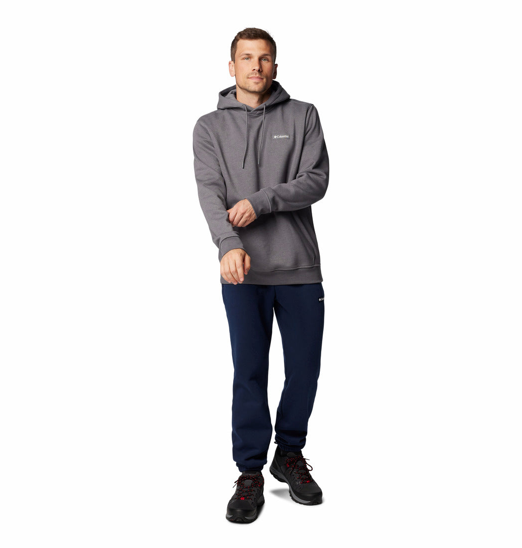 Man wearing a gray hoodie and navy pants on a white background