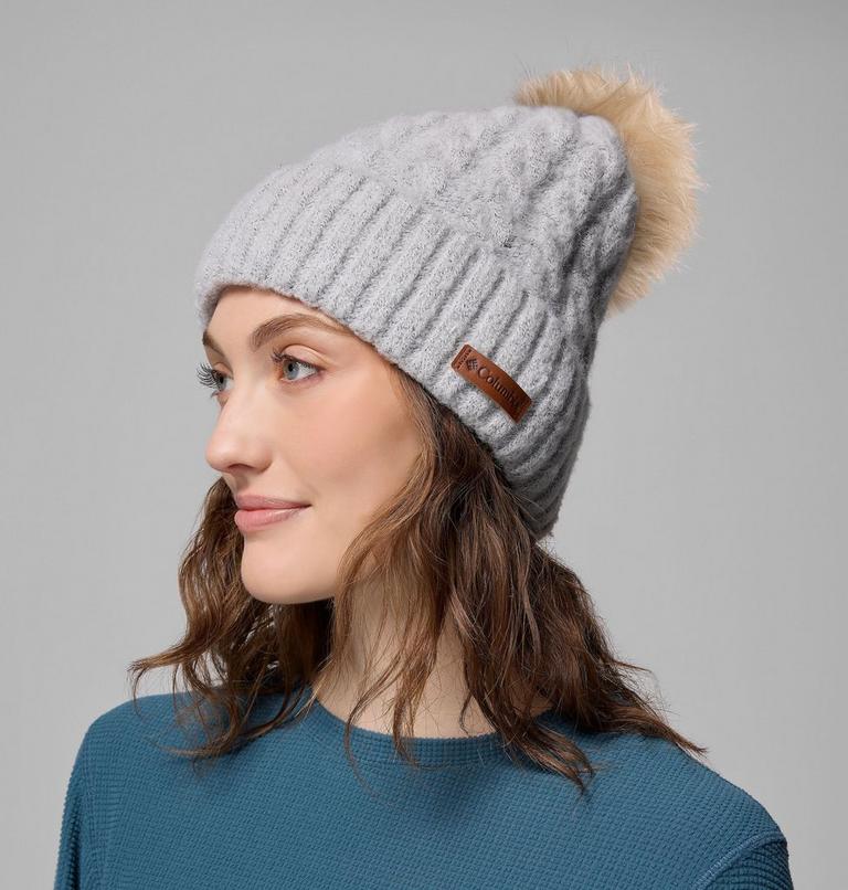 Woman wearing a gray knit beanie with a fur pom-pom on a gray background