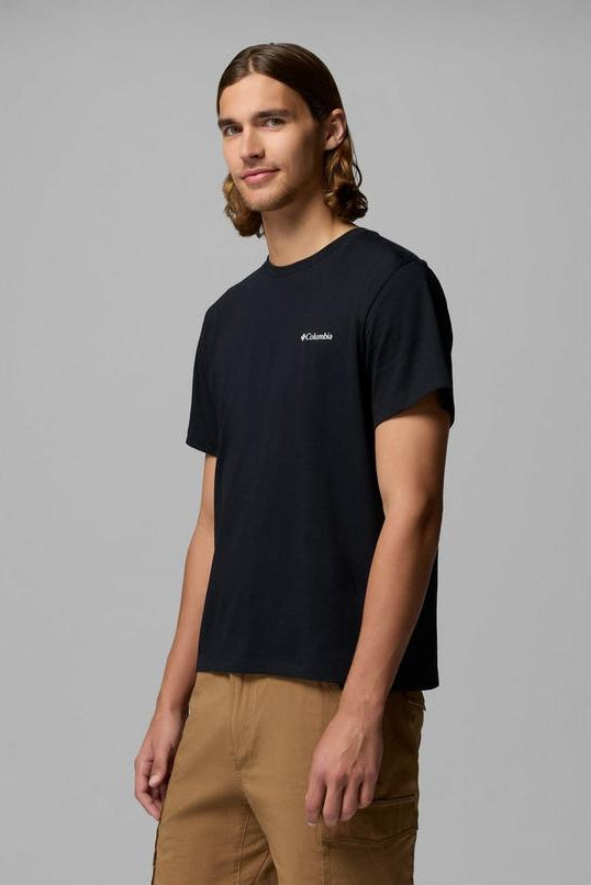 Person wearing a black t-shirt with a brand logo on a gray background