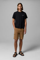 Man wearing a black t-shirt and brown cargo shorts on a gray background