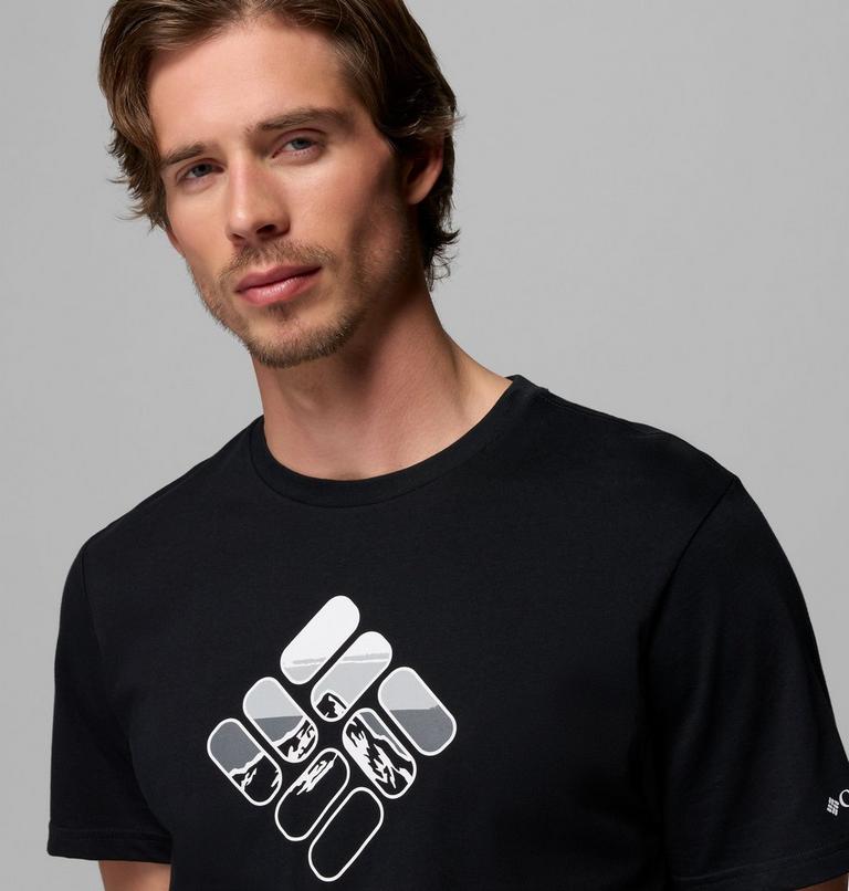 Man wearing a black t-shirt with a white logo on a gray background