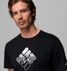Man wearing a black t-shirt with a white logo on a gray background