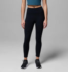 Person wearing black leggings and a blue top on a gray background
