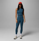 Woman wearing a teal athletic outfit with a red cap on a gray background