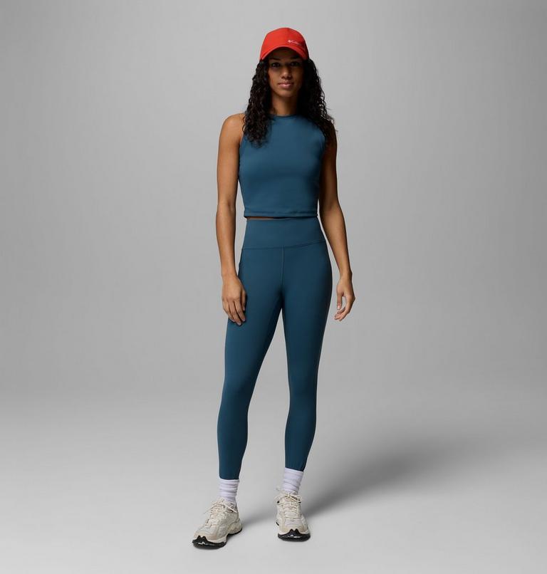 Woman wearing a teal athletic outfit with a red cap on a gray background