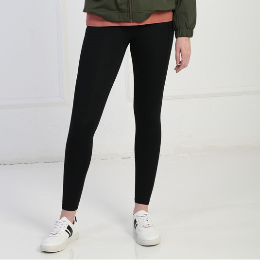 Person wearing black leggings and white sneakers on a white background