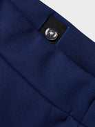 Close-up of a blue fabric pant with a button adjuster on the waistband on a white background
