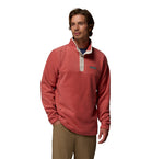 Man wearing a red fleece pullover with a visible brand logo on a white background