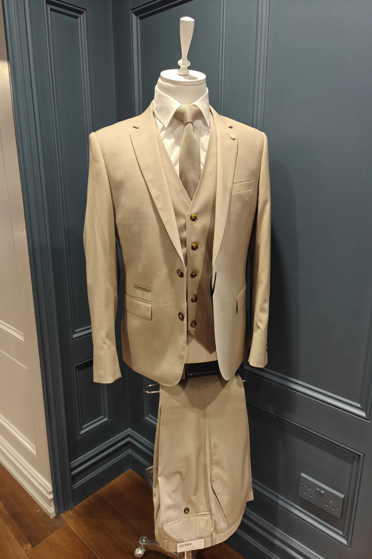 Kingsley walnut 3 piece suit from 6th Sense on a mannequin against a dark blue paneled wall.