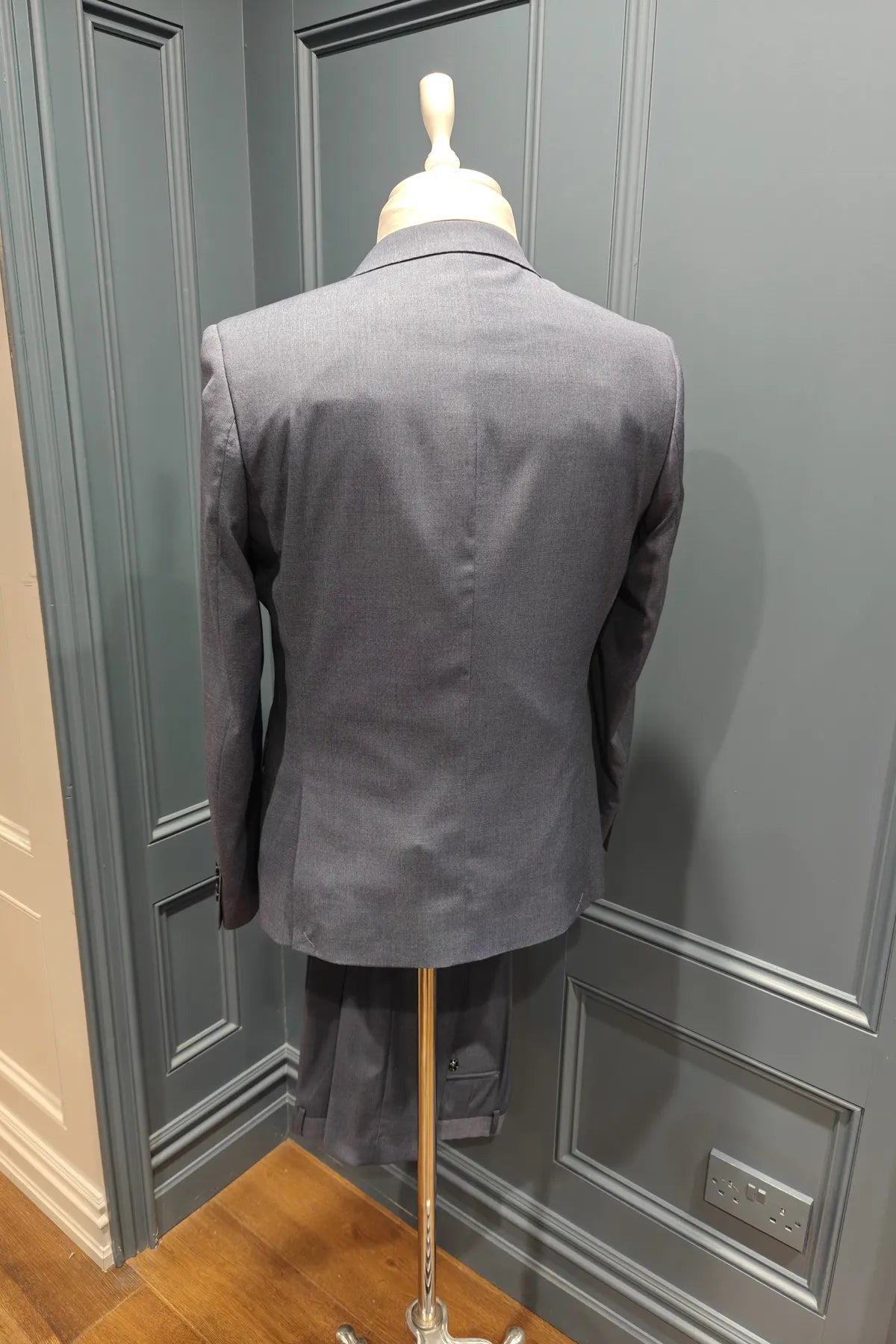 Kingsley Indigo suit jacket on a mannequin against a gray paneled wall.