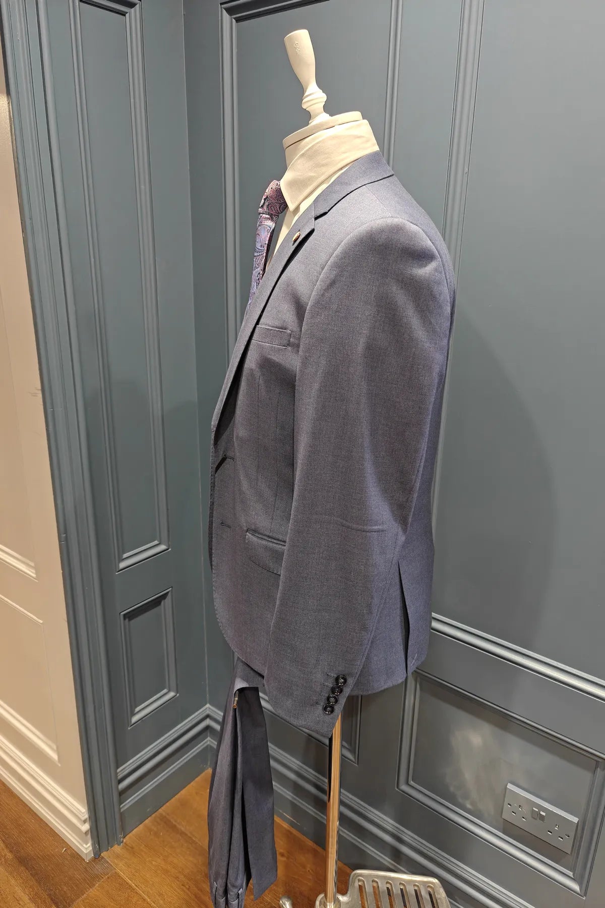 Kingsley Indigo suit on a mannequin against a gray wall. Side view