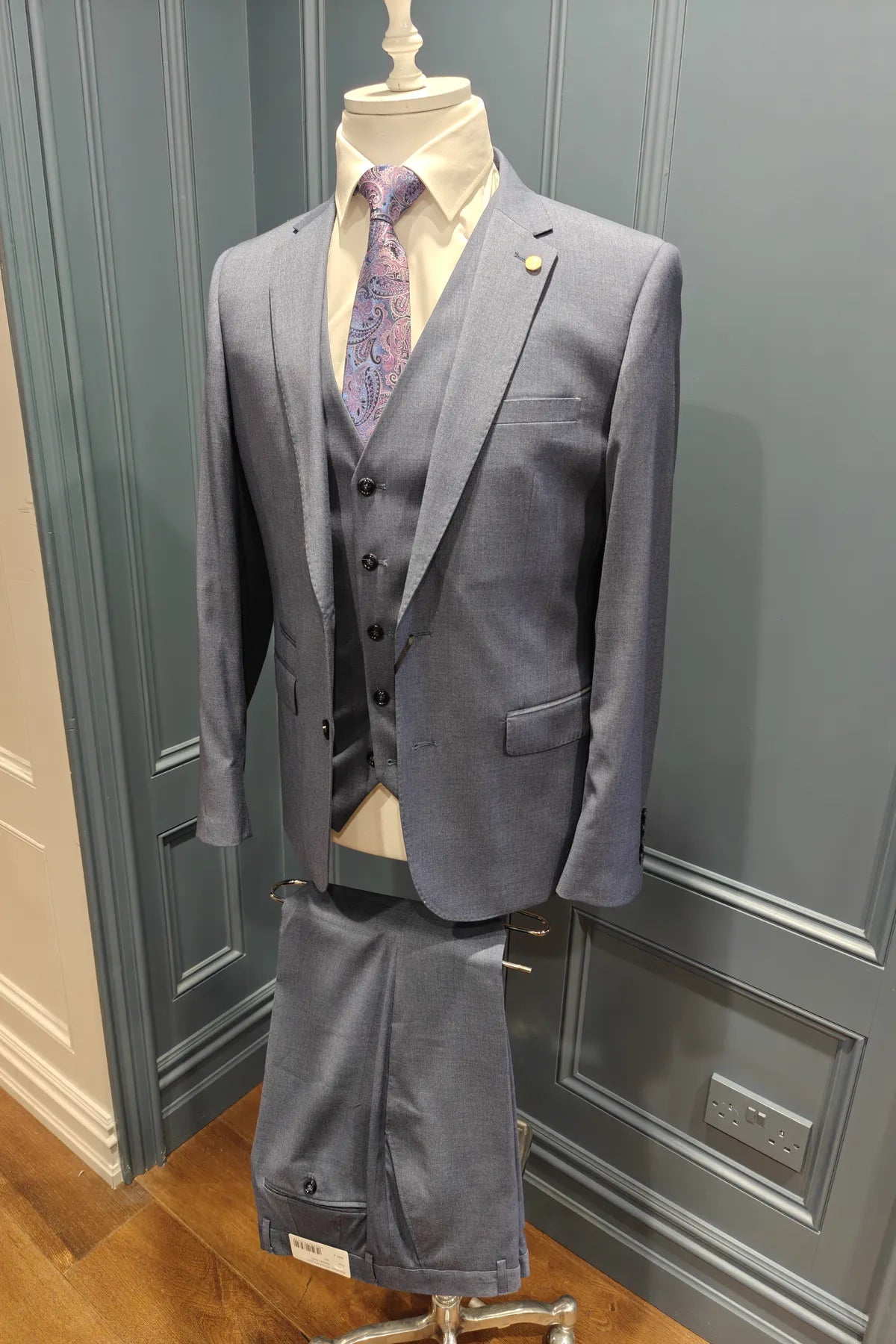 Kingsley Indigo suit on a mannequin against a gray paneled wall.