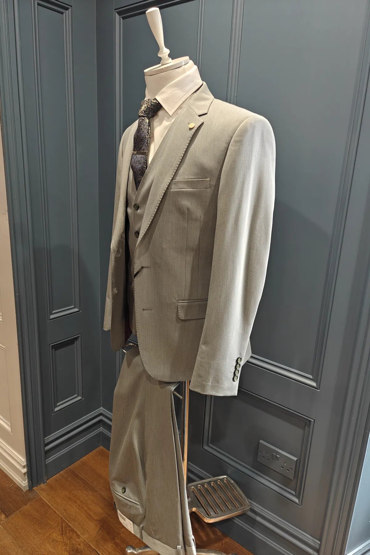 Windsor shade green 3 piece suit on a mannequin against a gray paneled wall. Side view