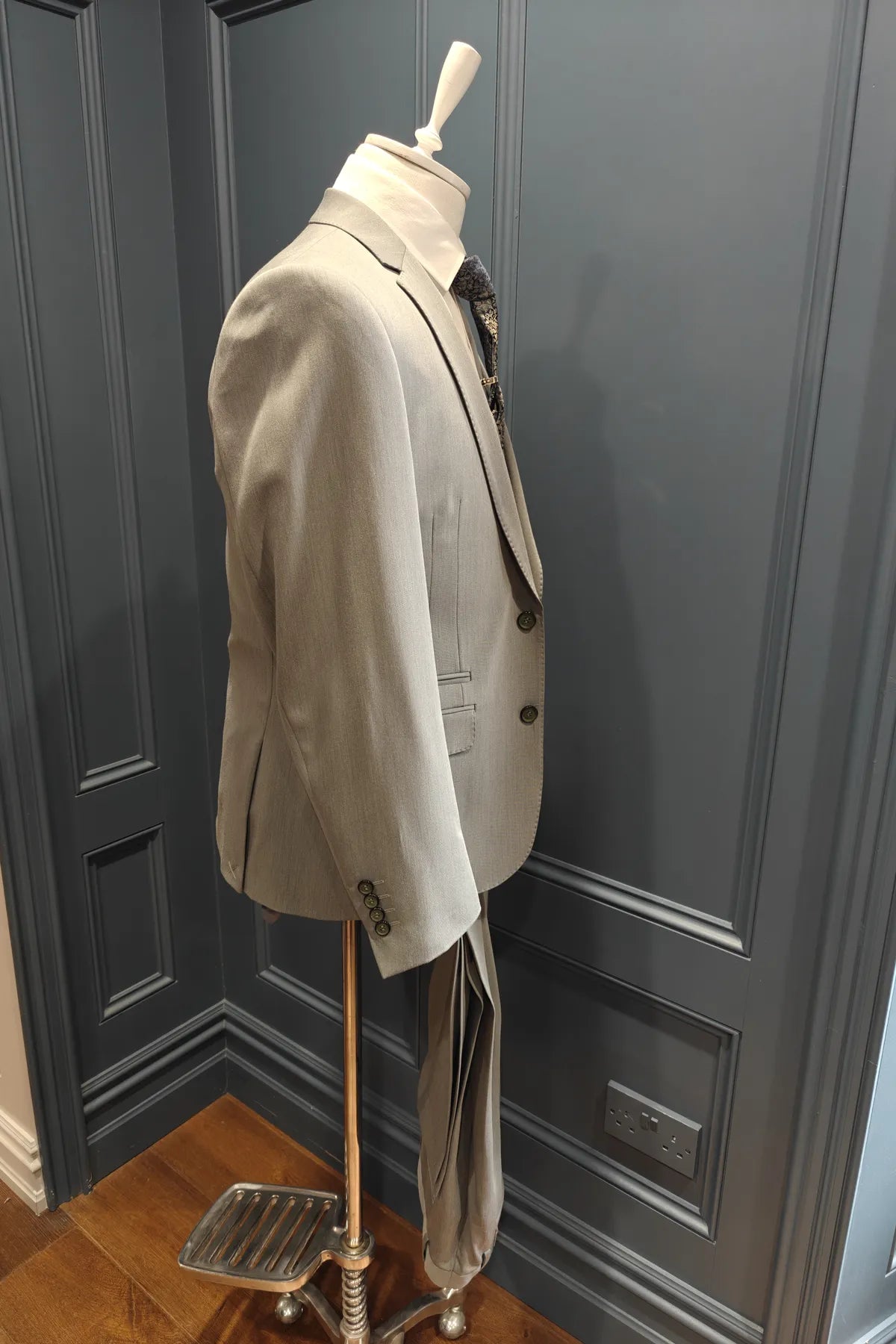 Windsor shade green 3 piece suit on a mannequin against a gray paneled wall. Angle view