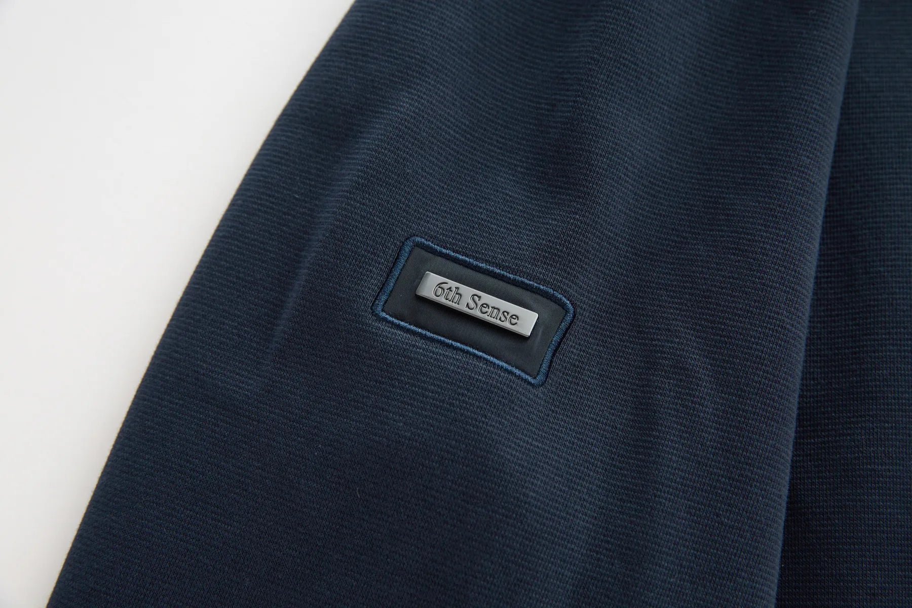 Navy blue fabric with a '6th Sense' label on a white background