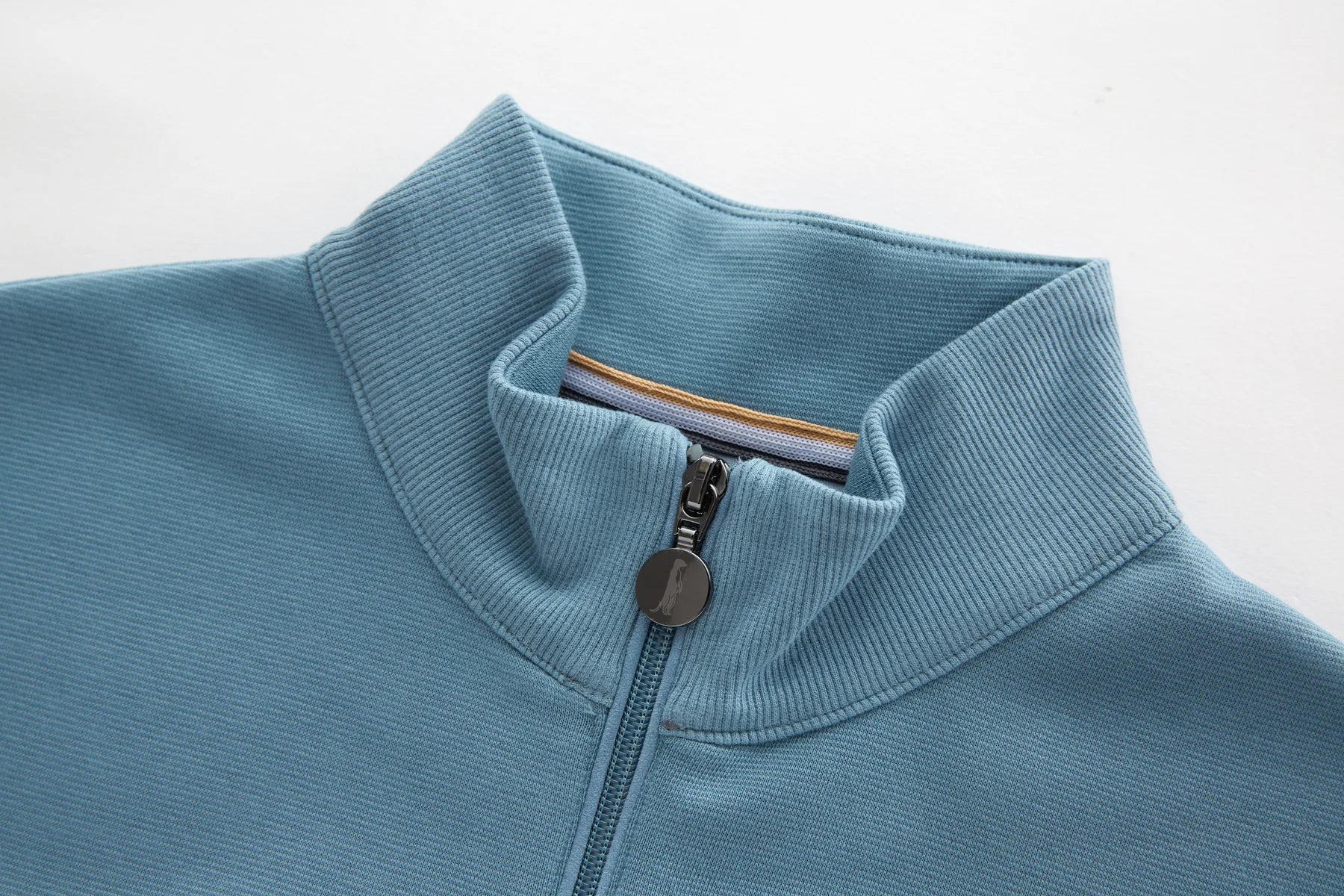 Close-up of a Belter Smoke 1/4 Zip sweater collar with a zipper on a light gray background