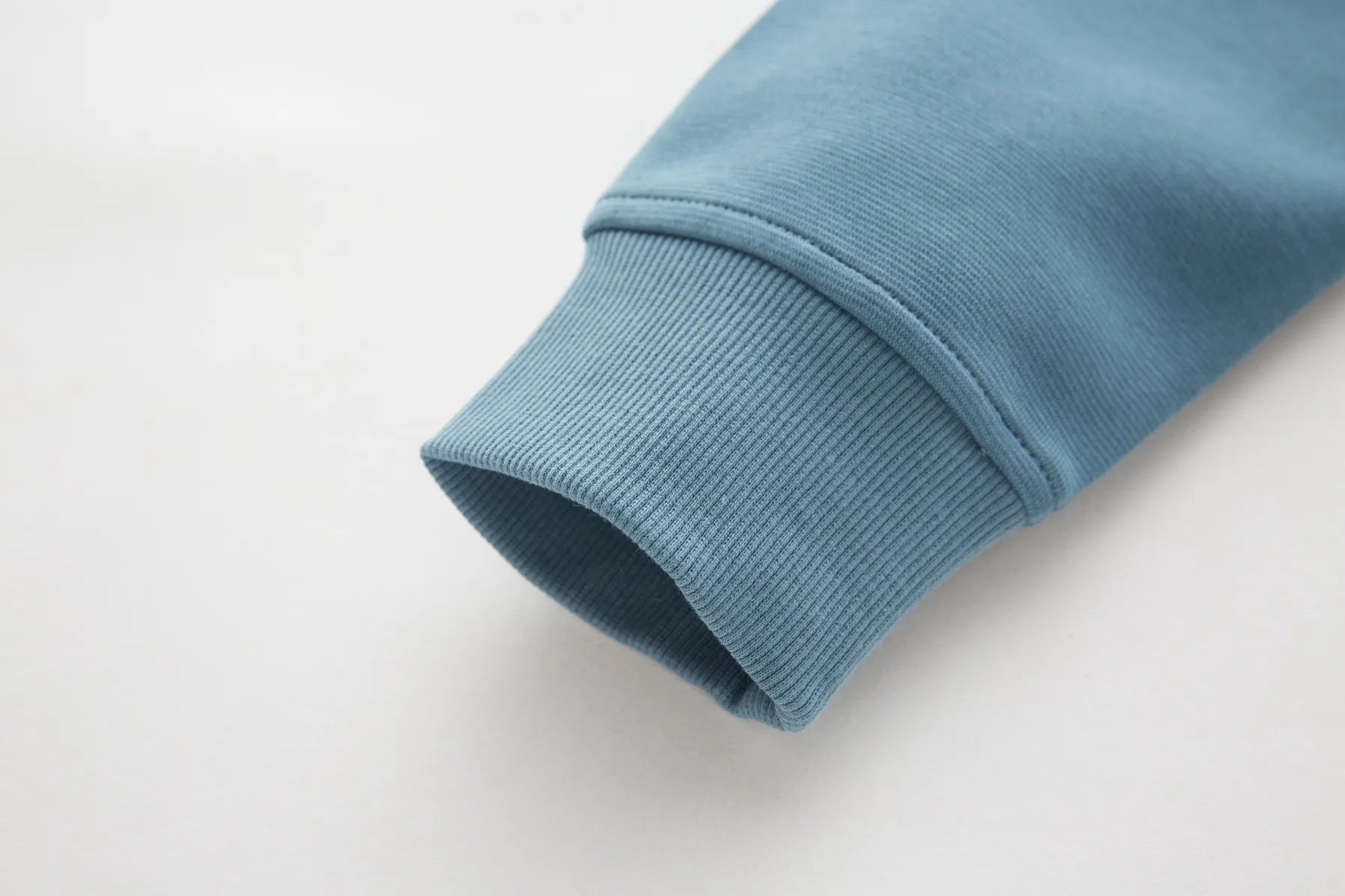 Close-up of a Belter Smoke 1/4 Zip sleeve on a light gray background